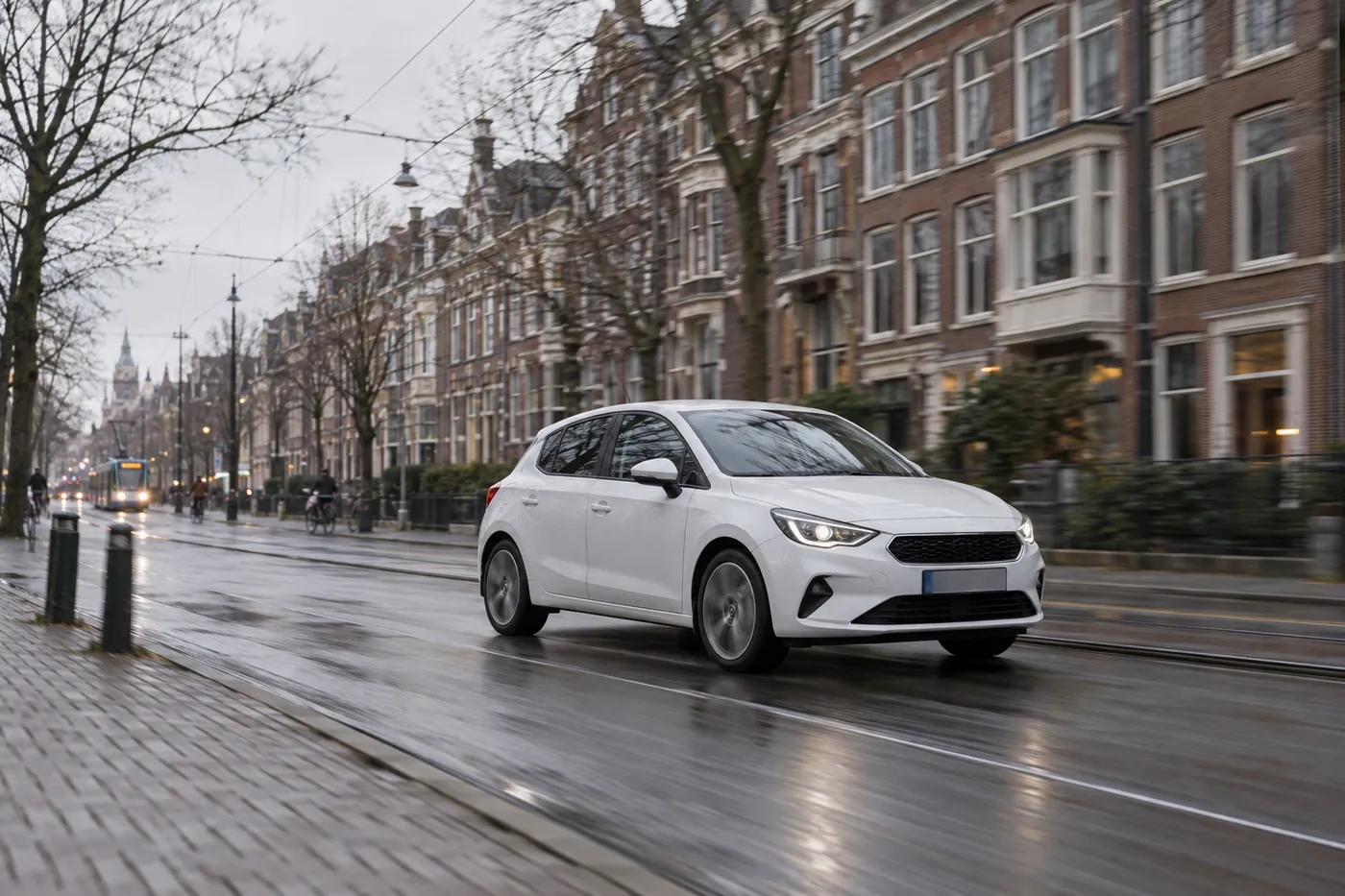 A white hatchback driving along a street of brick townhouses